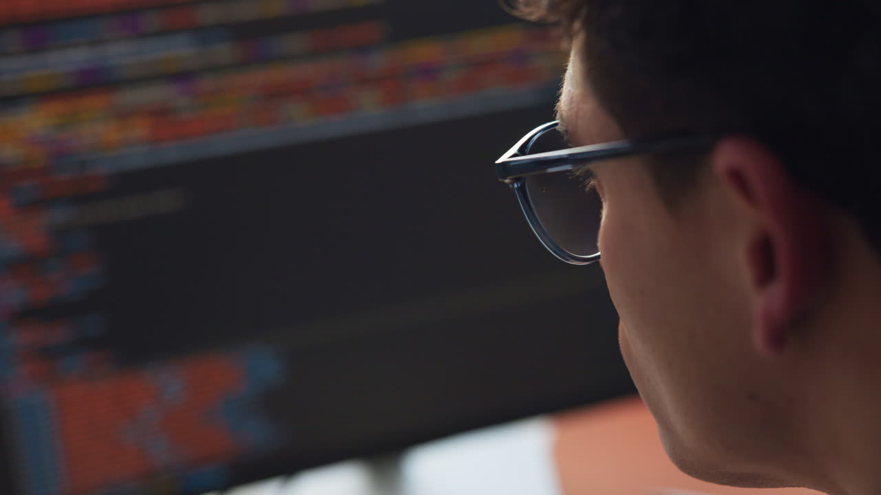 Uomo con gli occhiali che guarda lo schermo del computer con il codice