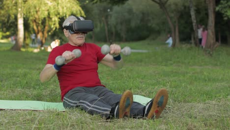 anciano abuelo hombre en casco auricular vr haciendo ejercicios de fitness con pesas en el parque