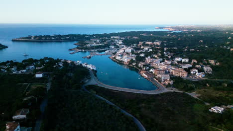 Vista-Aérea-De-Portopetro,-Mallorca-Al-Atardecer-Con-Agua-Serena-Y-Edificios.