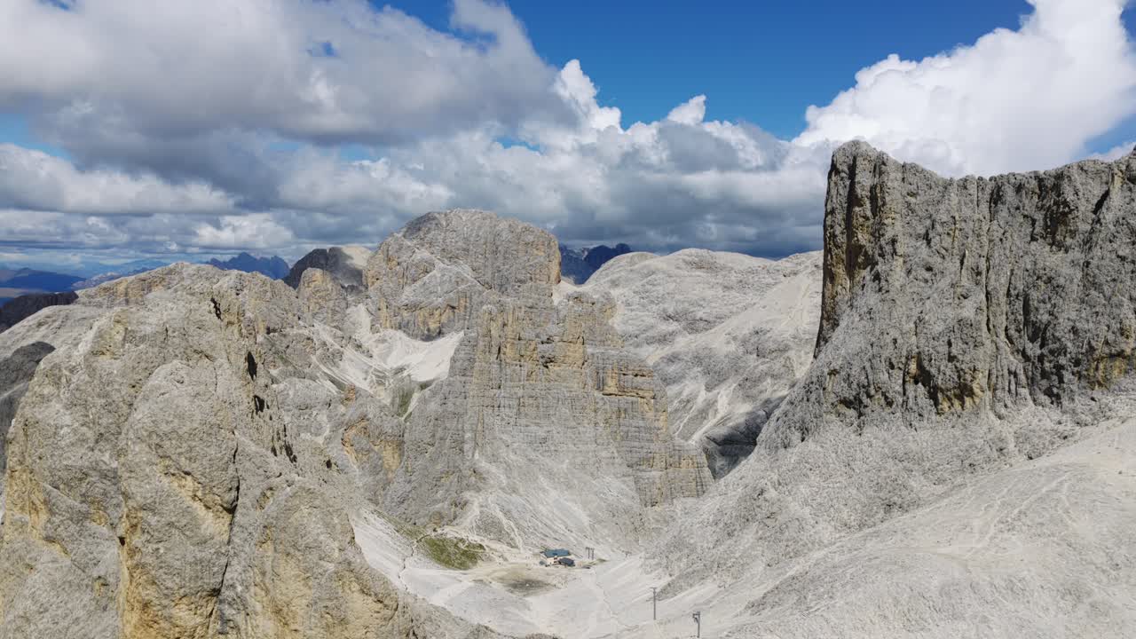 Vertical aerial reveals Rifugio Re Alberto I mountain refuge nestled among dramatic rock peaks of Vajolet Towers, Dolomites, Italy