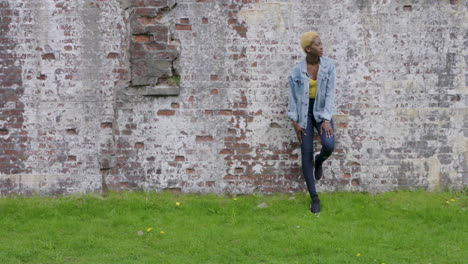 stylish, young, woman standing by a stone wall, then walks away