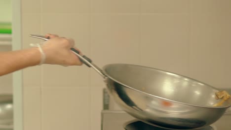 cook prepares fresh vegetables in a frying pan tosses them to mix