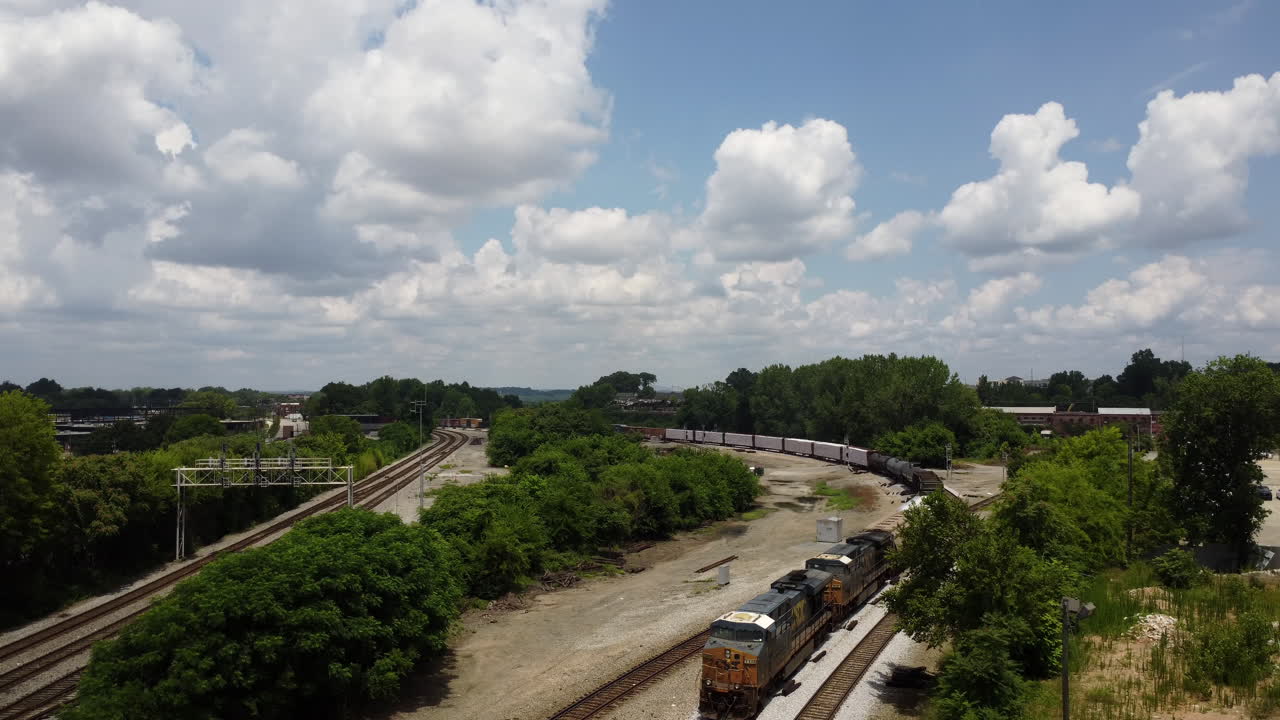 toma frontal aérea de un tren que pasa durante un cálido día de verano con muchas nubes visibles