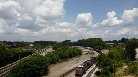 Toma-Frontal-Aérea-De-Un-Tren-Que-Pasa-Durante-Un-Cálido-Día-De-Verano-Con-Muchas-Nubes-Visibles