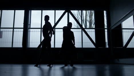 silhouette dancers performing hip hop in dark studio. guy and girl dancing .