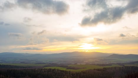 Time-lapse-of-clouds-moving-fast-above-a-mountain-village,-during-sunset