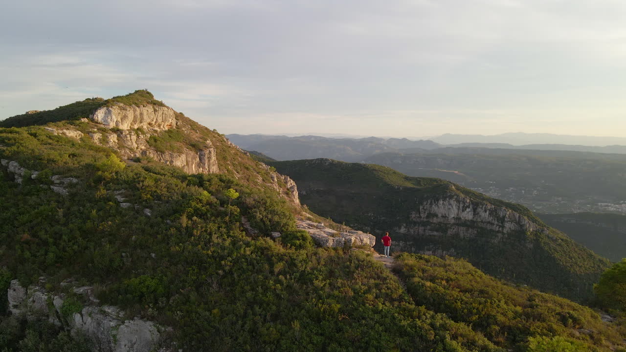 산 가장자리에 서서 풍경을 감상하는 사람의 공중 전망
