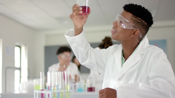 Teenage biracial boy examines a test tube in a high school lab
