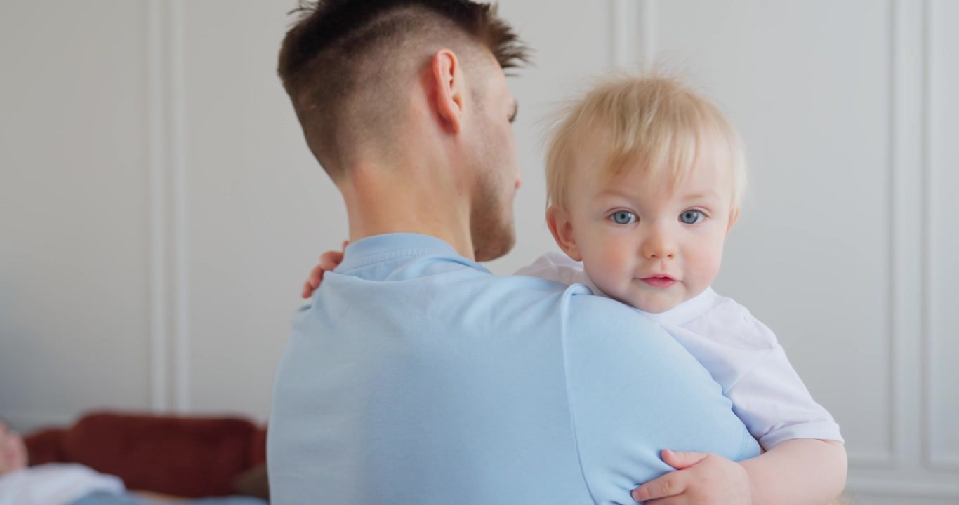 Padre felice che tiene in braccio il suo bambino a casa.