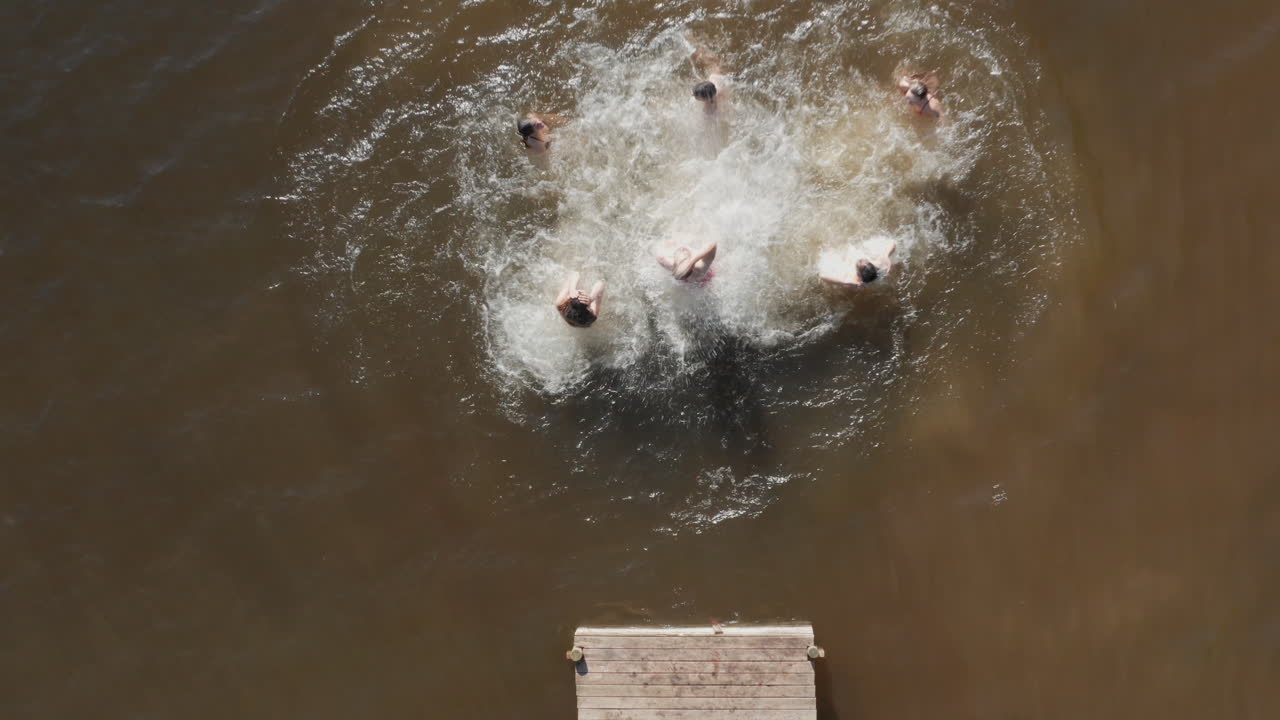 vista aérea amigos saltando del muelle en el lago divirtiéndose salpicándose en el agua disfrutando de la libertad en las vacaciones de verano vista aérea de drones desde arriba