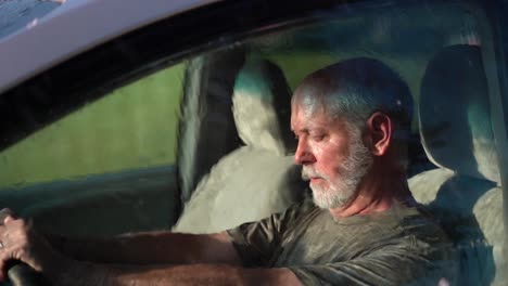 very sad man sitting in automobile dealing with depression as rain hits the windshield in slow motion