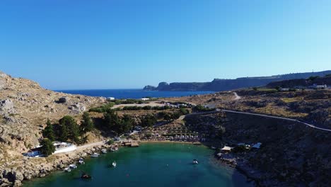 Agios-Pavlos-beach-in-Rhodes,-Greece-with-Acropolis-of-Lindos,-houses-and-Mediterranean-sea-during-the-day-filmed-with-the-drone