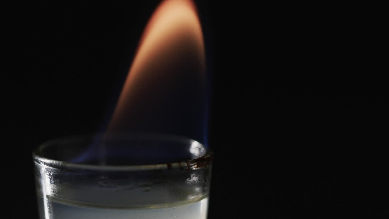 видео с зажженным алкоголем в стакане с оранжевым огненным пламенем и копированием пространства на черном фоне