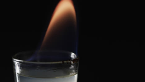 video de alcohol encendido en vidrio con llama de fuego naranja y copia de espacio en fondo negro