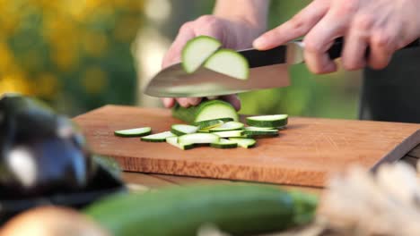 Un-Joven-Cortando-Calabacines-En-Una-Tabla-De-Madera-En-Su-Jardín-De-Cerca.