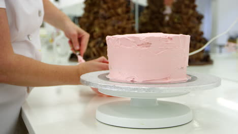 primer plano de una mujer en una panadería decorando un pastel con glaseado