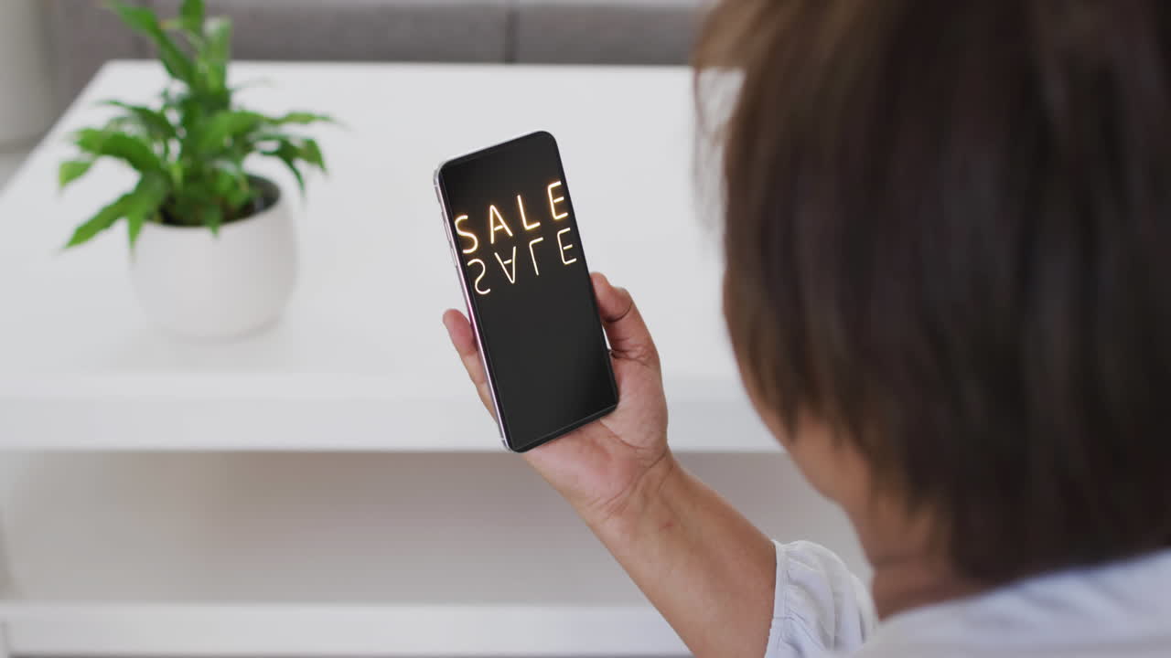 온라인 쇼핑을 위해 스마트폰을 사용하는 집에서 두 인종의 여성, 느린 동작