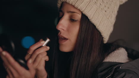 beautiful young caucasian woman applying lipstick makeup using mirror preparing for evening party