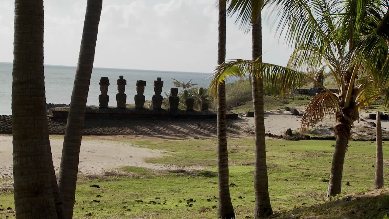 Le statue dell'Isola di Pasqua si ergono in una lunga fila su una spiaggia lontana.