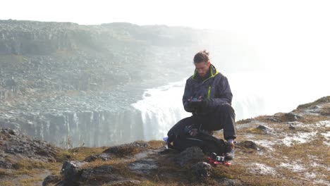 aerial orbiting shot of a drone pilot standing in front of a waterfall in iceland