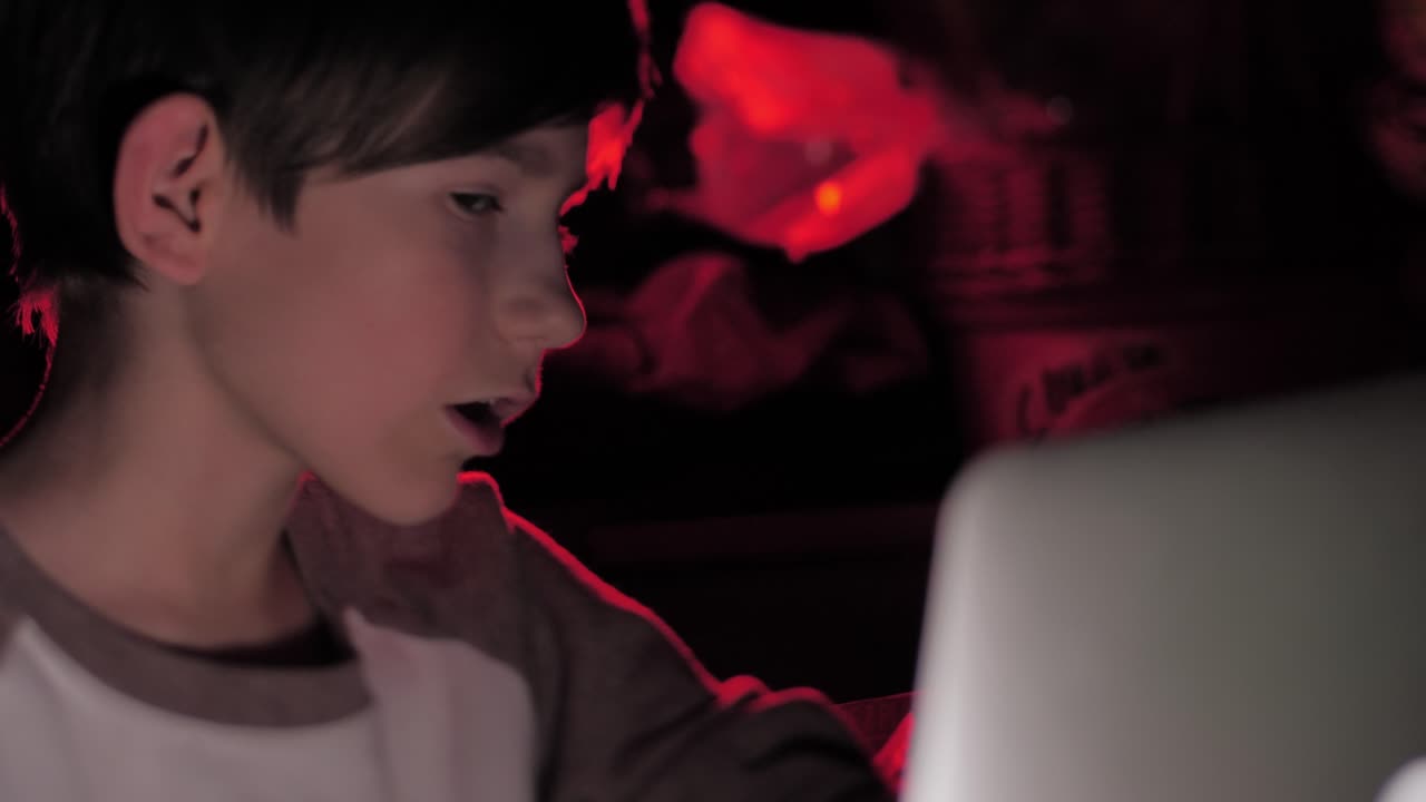 한 아이가 어둠 속에서 컴퓨터 앞에 앉아 있다