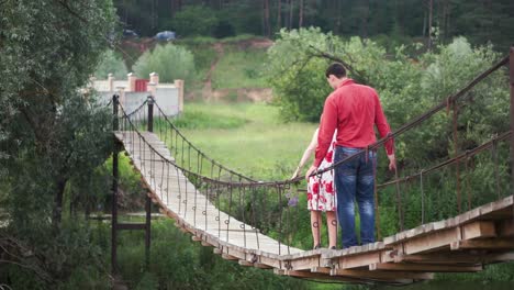 couple walking across a suspension bridge in a forest