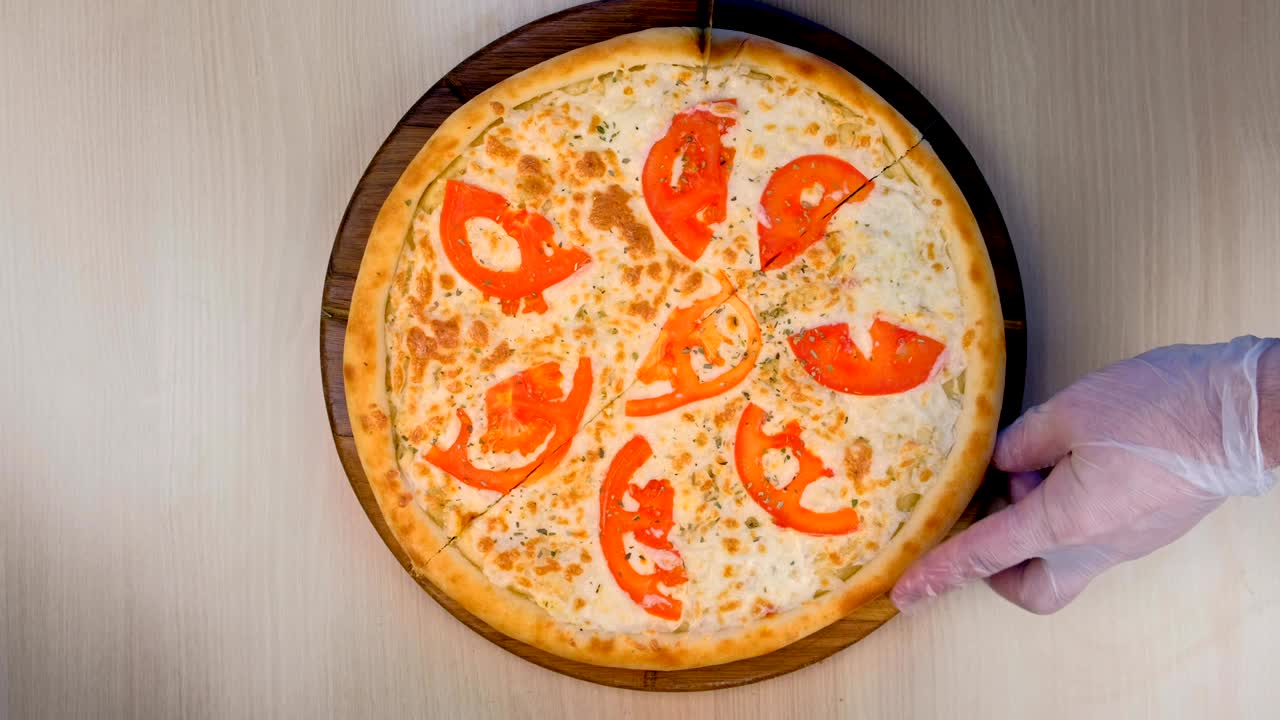 요리사는 토마토와 치즈를 가진 피자를 나무판 위에 어 니다.