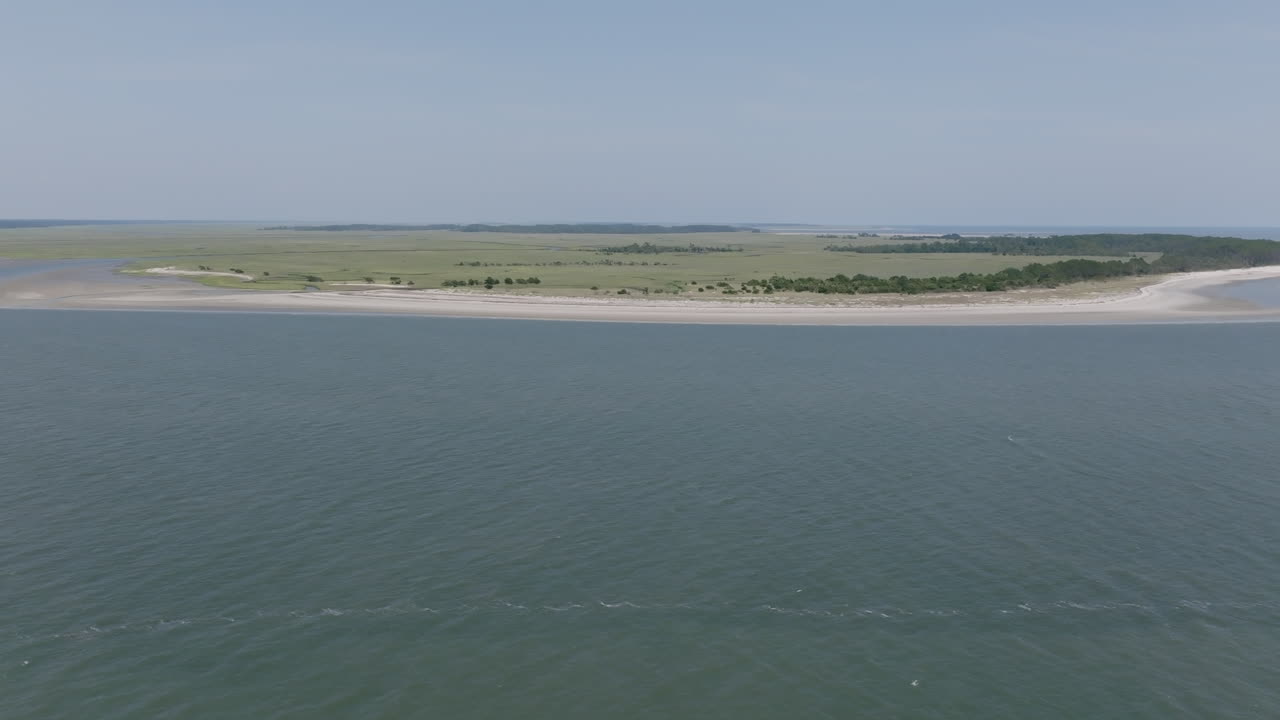 An inlet opens to wide, protected marshland across the water, with grassy textures and undisturbed shoreline winding into the horizon