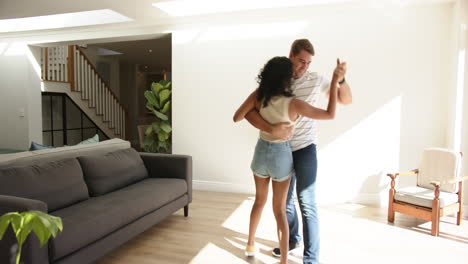 dancing together, young multiracial couple enjoying time in bright living room, at home