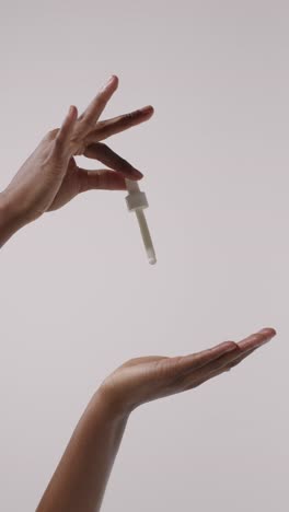 close up of woman squeezing dropper from bottle of beauty product on white background 1