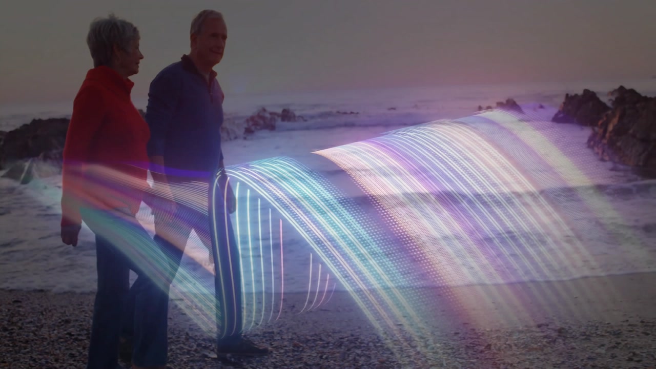Senior couple walking dusk shore in tech demo while emerging colorful light enveloping them