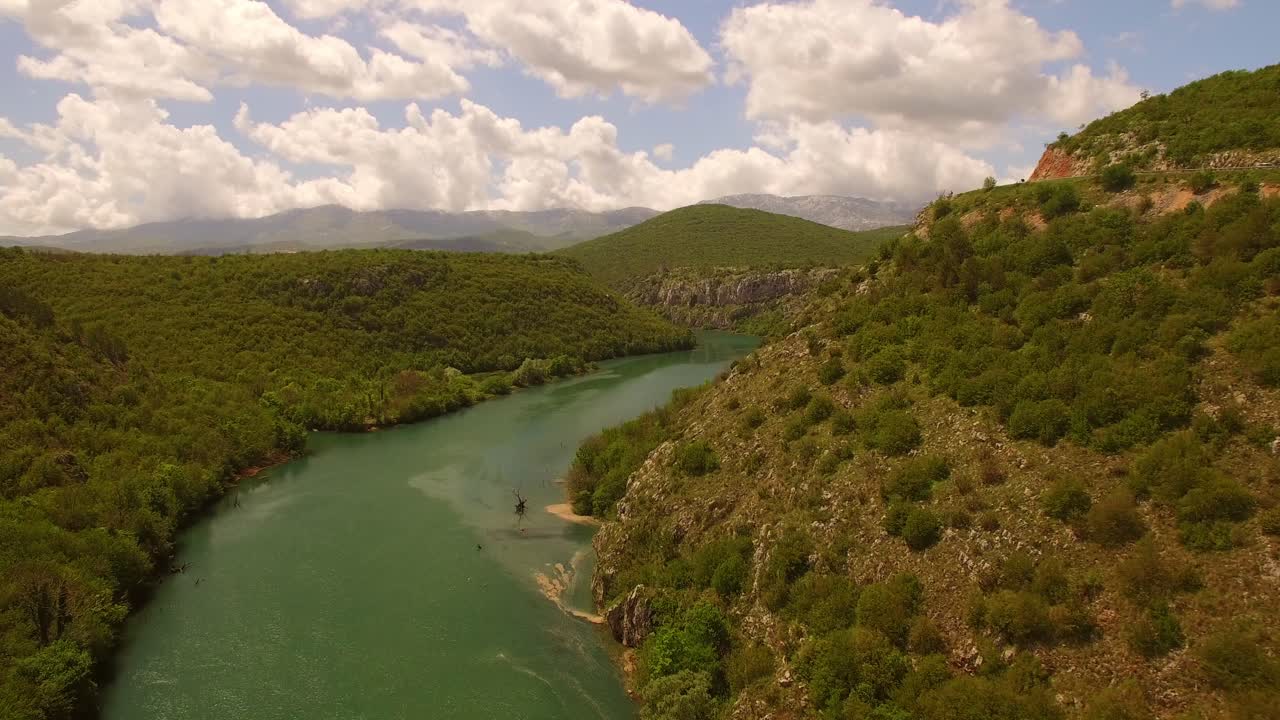 drone sobre río, naturaleza verde y cielo lleno de nubes
