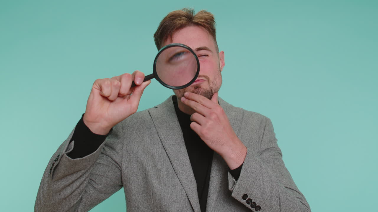 Investigator researcher man with magnifying glass near face looking into camera with big zoom eye