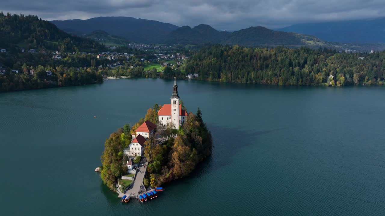 Panoramiczne ujęcie z lotu ptaka wyspy na jeziorze Bled z Kościołem Wniebowzięcia NMP, otoczonej alpejskim krajobrazem w Słowenii.