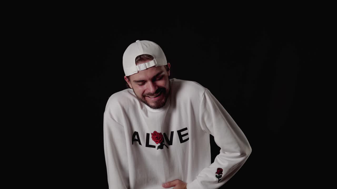 hombre moderno de 20 años riéndose a carcajadas, gesto feliz, fondo ancho y negro.