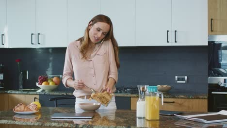 mujer feliz preparando un desayuno saludable. persona relajada hablando por teléfono móvil