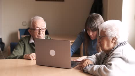 young woman teaching senior people using laptop