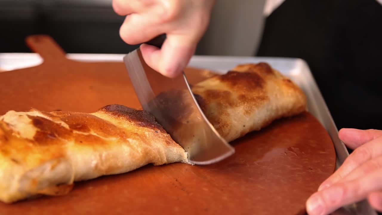 Cortando un calzone dorado con un cuchillo mecedora