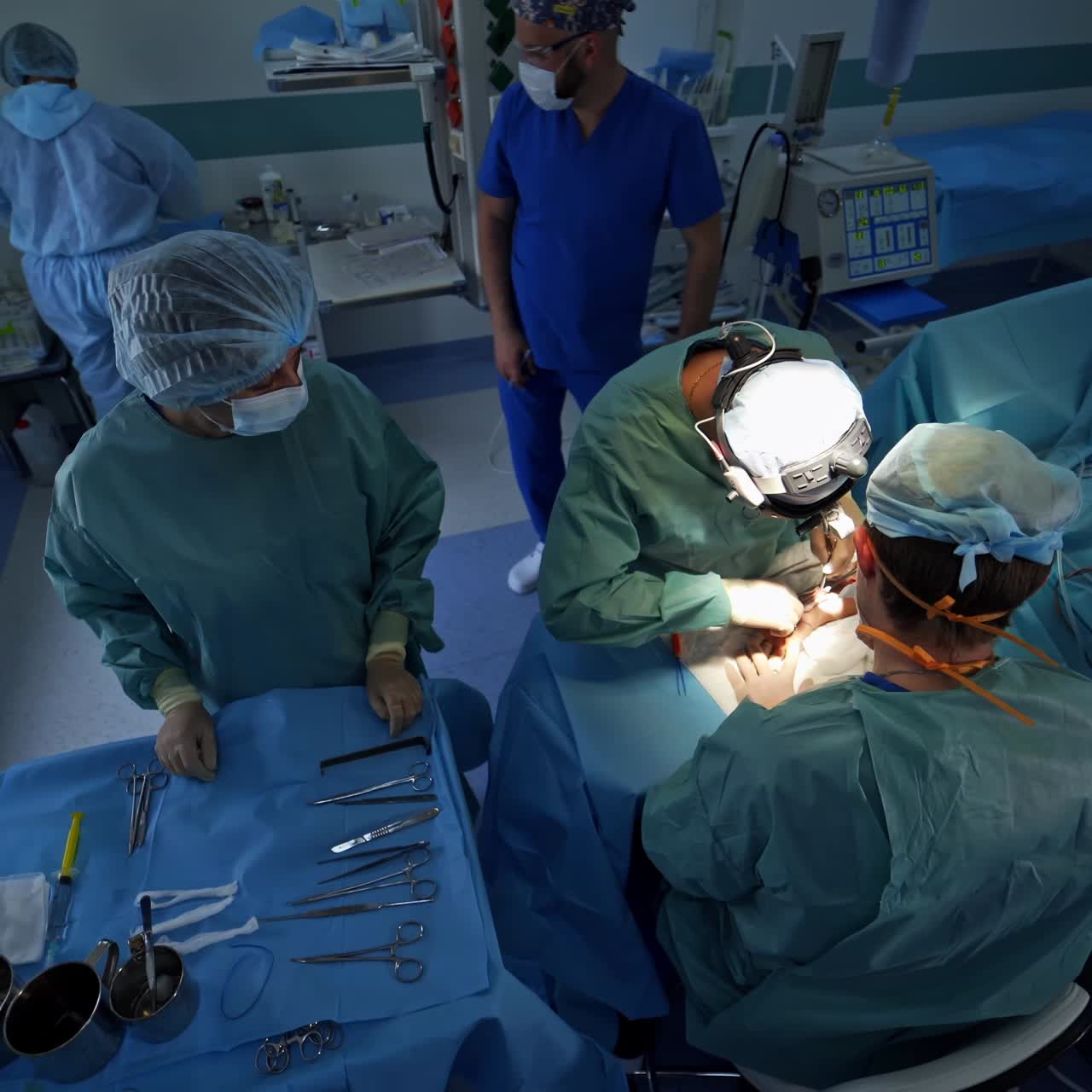 Professional surgeons conducting operation on patient's arm. Assisting nurse standing beside. High angle view