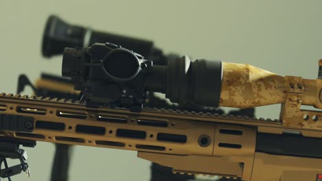 black scope on top of a beige, army tinted rifle