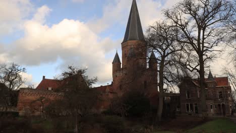 Sich-Schnell-Bewegende-Wolken-In-Einem-Zeitraffer,-Der-Die-Mittelalterliche-Stadtmauer-Und-Den-Spitzen-Turm-Mit-Spitzen-Des-Drogenapstoren-In-Der-Historischen-Stadt-Zutphen-In-Den-Niederlanden-Im-Schatten-Und-Im-Sonnenlicht-Zeigt