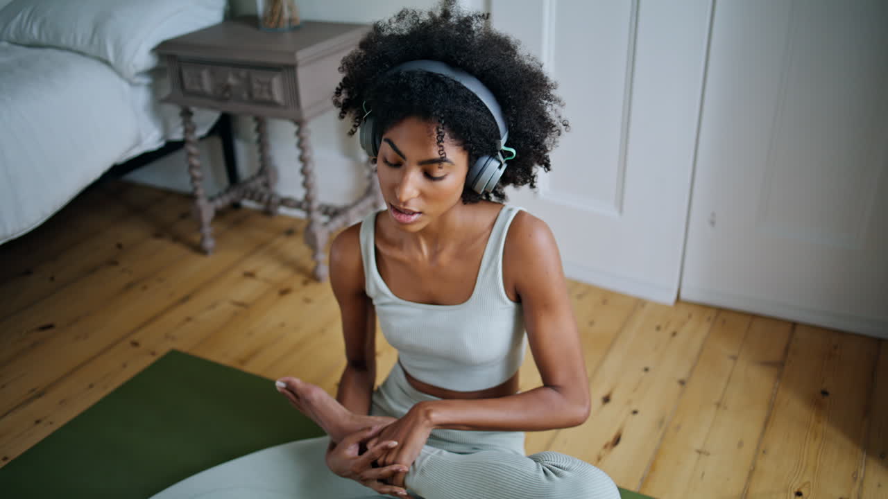 mujer relajada estirando las piernas dormitorio dama africana escuchando música meditando