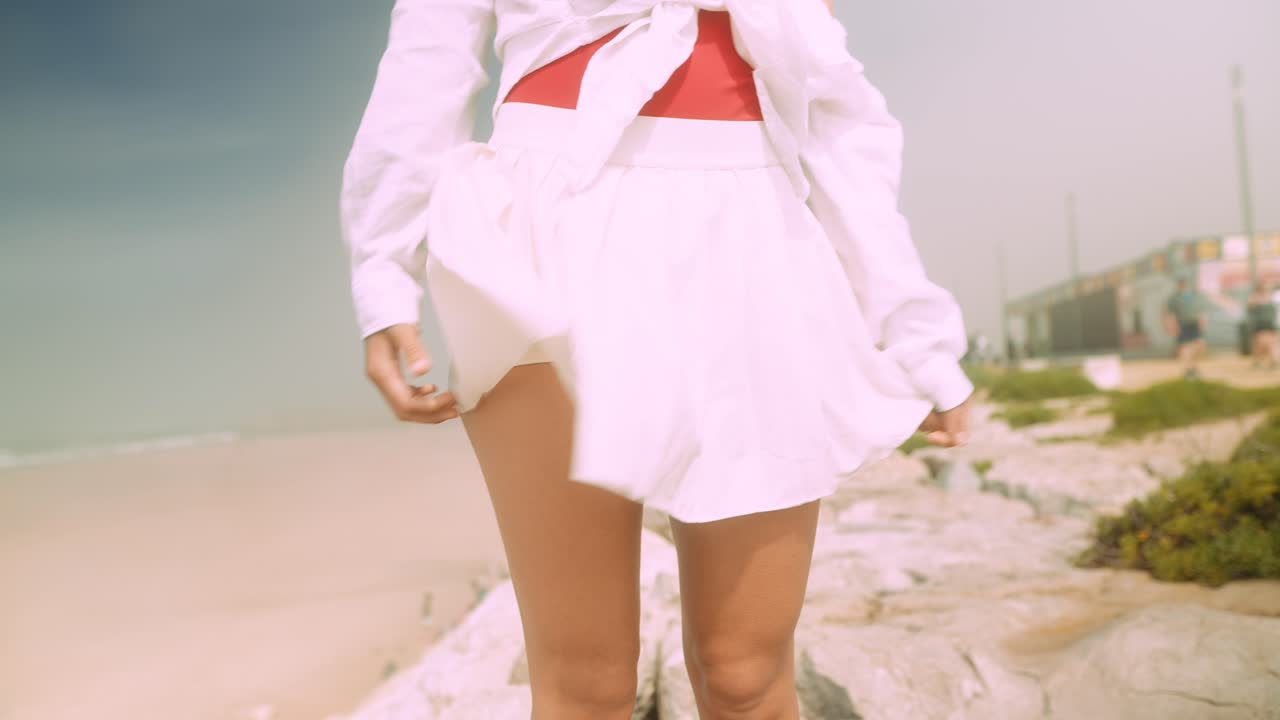 Giovane donna elegante in posa sugli scogli della spiaggia