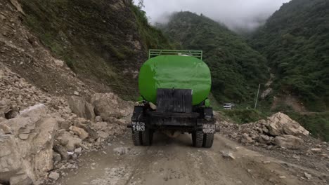 conduciendo por un camino accidentado de montaña en nepal siguiendo un camión de agua verde