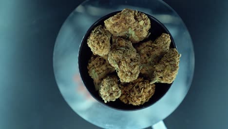 un zoom cinematográfico de arriba hacia abajo detallado en movimiento de una planta de cannabis, cepas híbridas de naranja, tipo indica, flor de marihuana, cámara lenta 120 fps, luces de estudio, soporte giratorio brillante