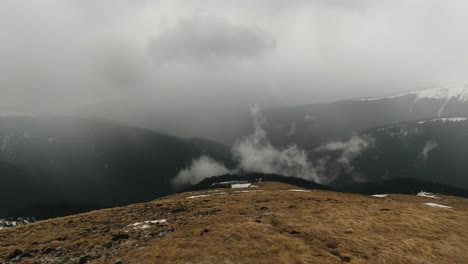 wide-angle panning right shot of mountain valley landscape with fog and clouds