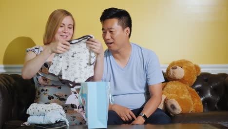 a pregnant woman with her husband looks at just that things bought for the baby expecting a baby buy