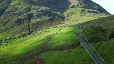 High-above-mountain-pass-with-light-traffic-and-cloud-shadows-moving-on-landscape-on-summer-day