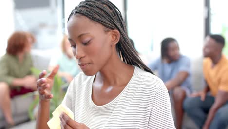 Emotional-woman-crying-with-diverse-friends-talking-in-background-during-group-therapy-session