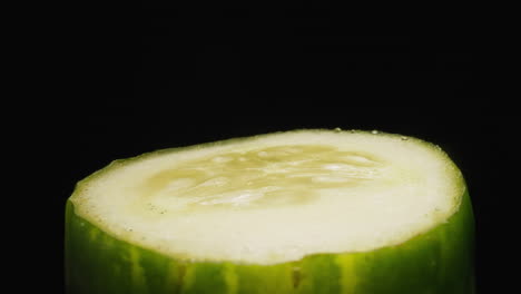 Cut-sluggish-cucumber-with-seeds-turning-on-black-background